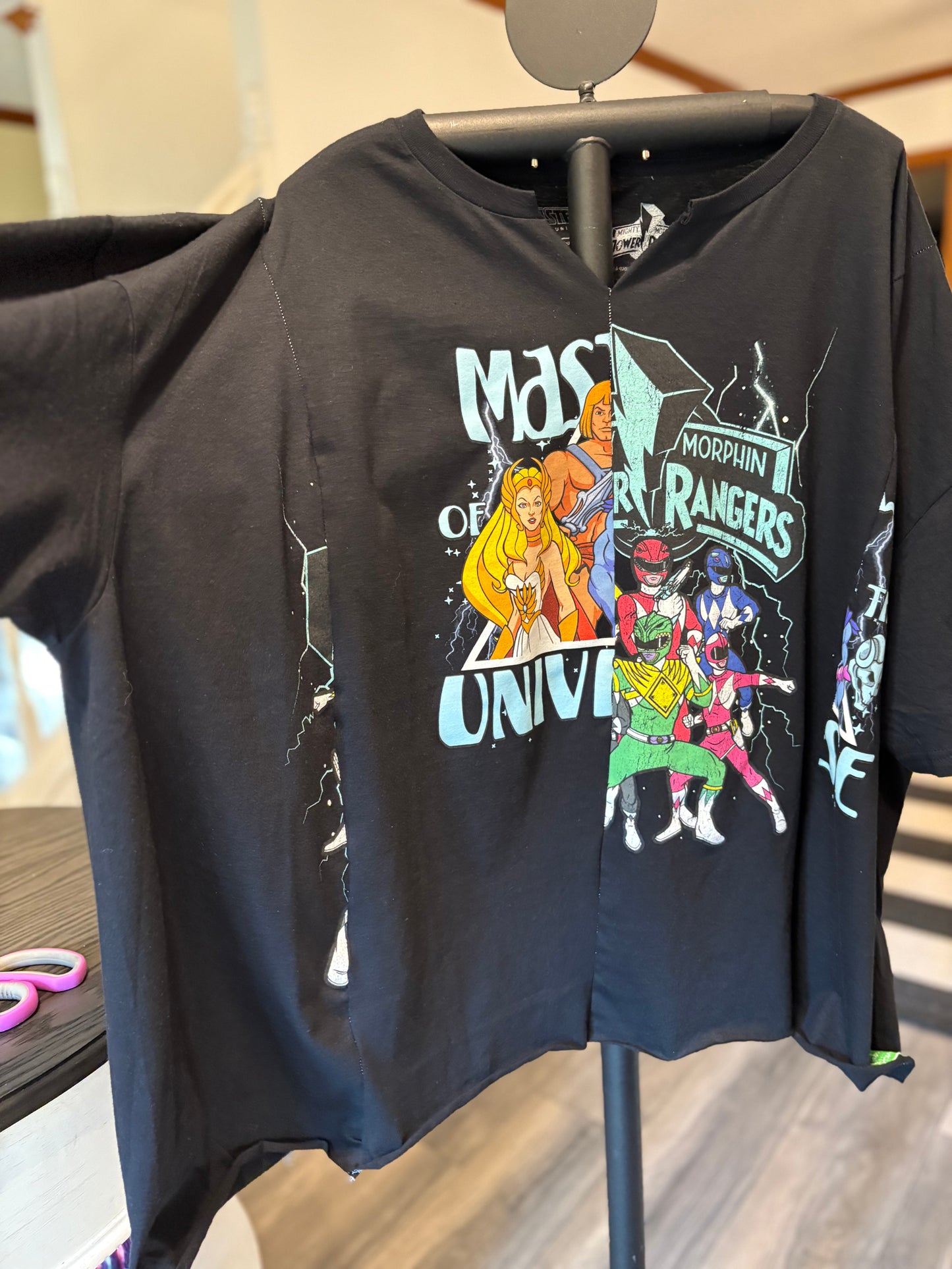 Black graphic tee featuring He-Man and Power Rangers, perfect for nostalgia lovers and pop culture fans. Sleeve