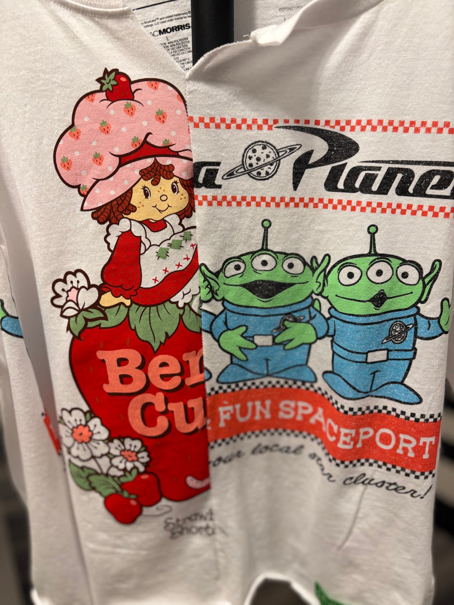 Vintage-inspired white tee featuring Strawberry Shortcake and Toy Story aliens, perfect for casual wear. Detail